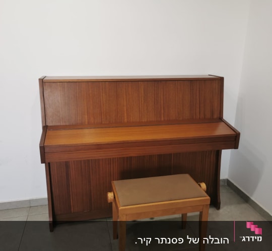 פסנתר עומד עם שרפרף עץ על רצפת אריחים